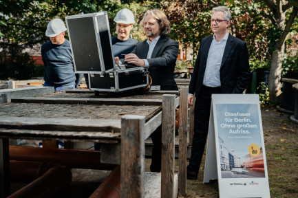 4 Männer, zwei davon mit Bauhelm, stehen vor einem geöffneten Koffer